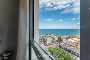 Vista da janela sobre um horizonte costeiro com edifícios e céu claro.