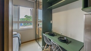 A modern kitchen with a dining area, a large window, and a view of greenery outside. - Your Complete Stay in Salvador, Steps From the sea - Saas (Salvador)