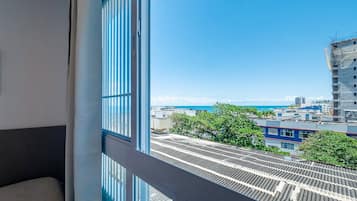 A view from a window of a building with a metal roof, a balcony, and a clear blue sky.