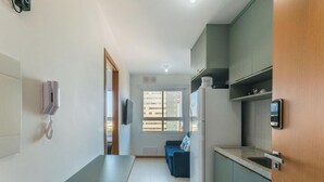 A narrow hallway with a kitchen area on the right, a blue sofa in the center, and a door leading to another room. - Your Complete Stay in Salvador, Steps From the sea - Saas (Salvador)
