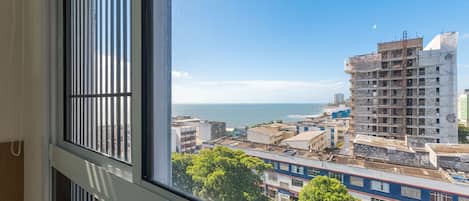 A view from a window overlooking a coastal cityscape with buildings and a clear sky.