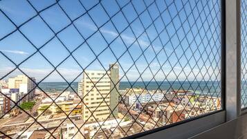 Paisagem urbana com edifícios e vista para o mar através de uma cerca de arame.