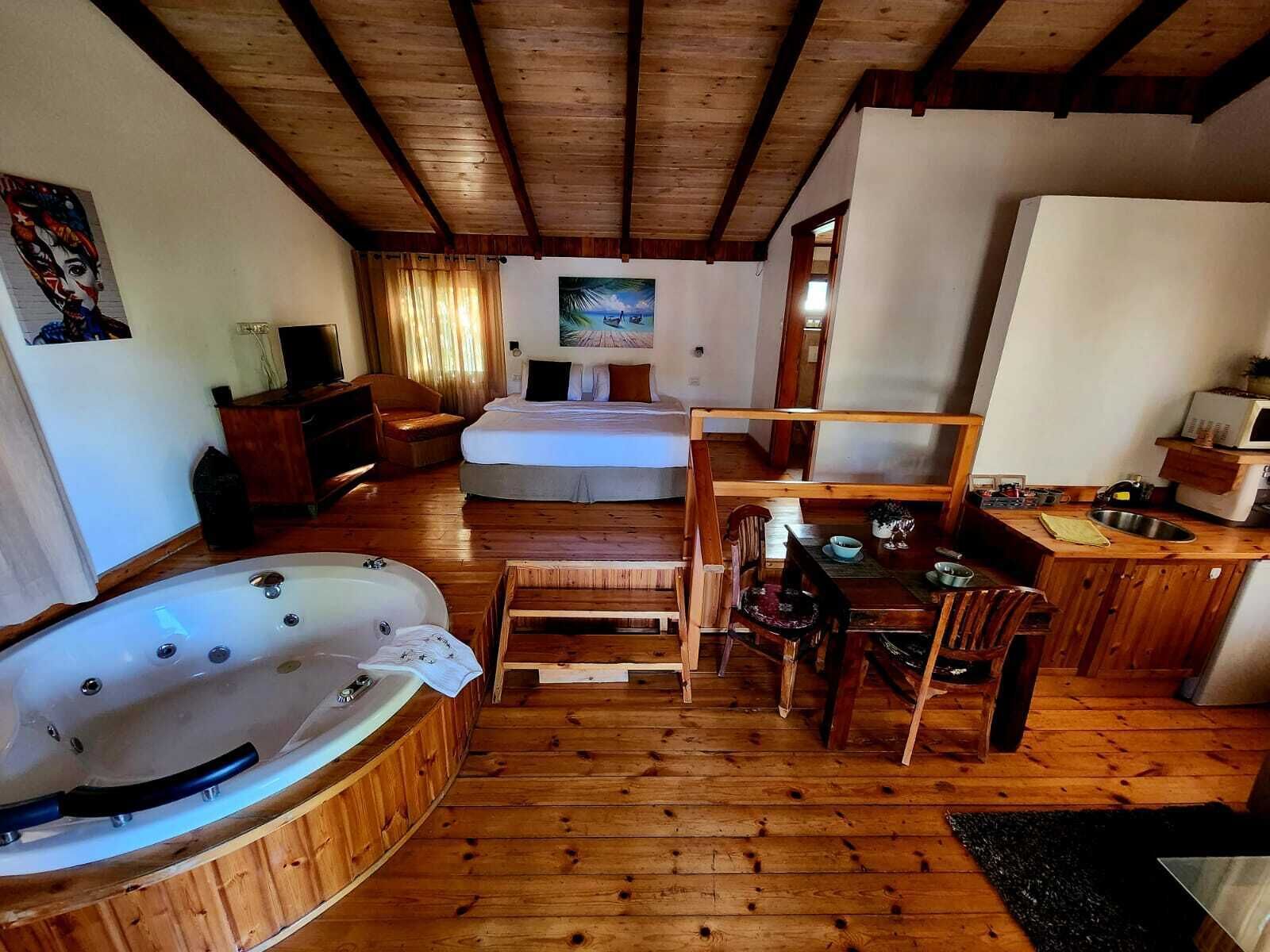 Een gezellig chalet met houten inrichting, een bubbelbad, een eethoek en een keuken.