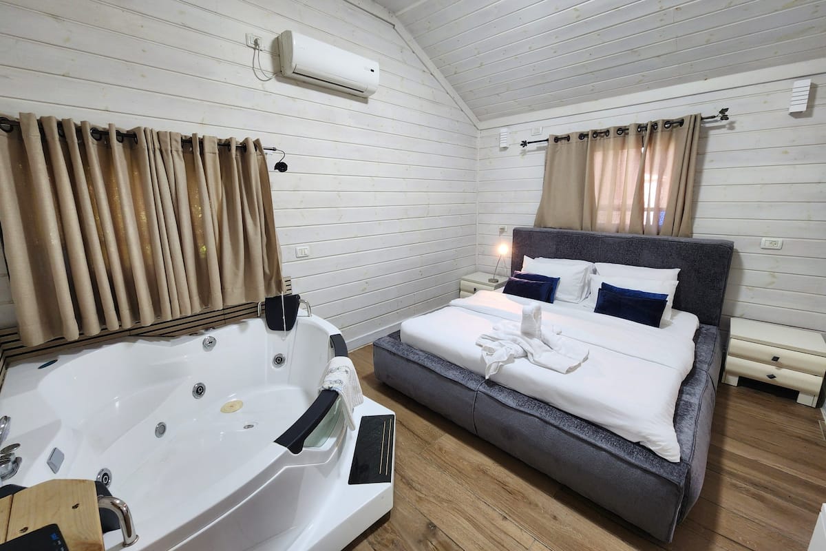 Une chambre dotée d’une grande baignoire, d’un lit avec de nombreux oreillers et d’une petite table de chevet.