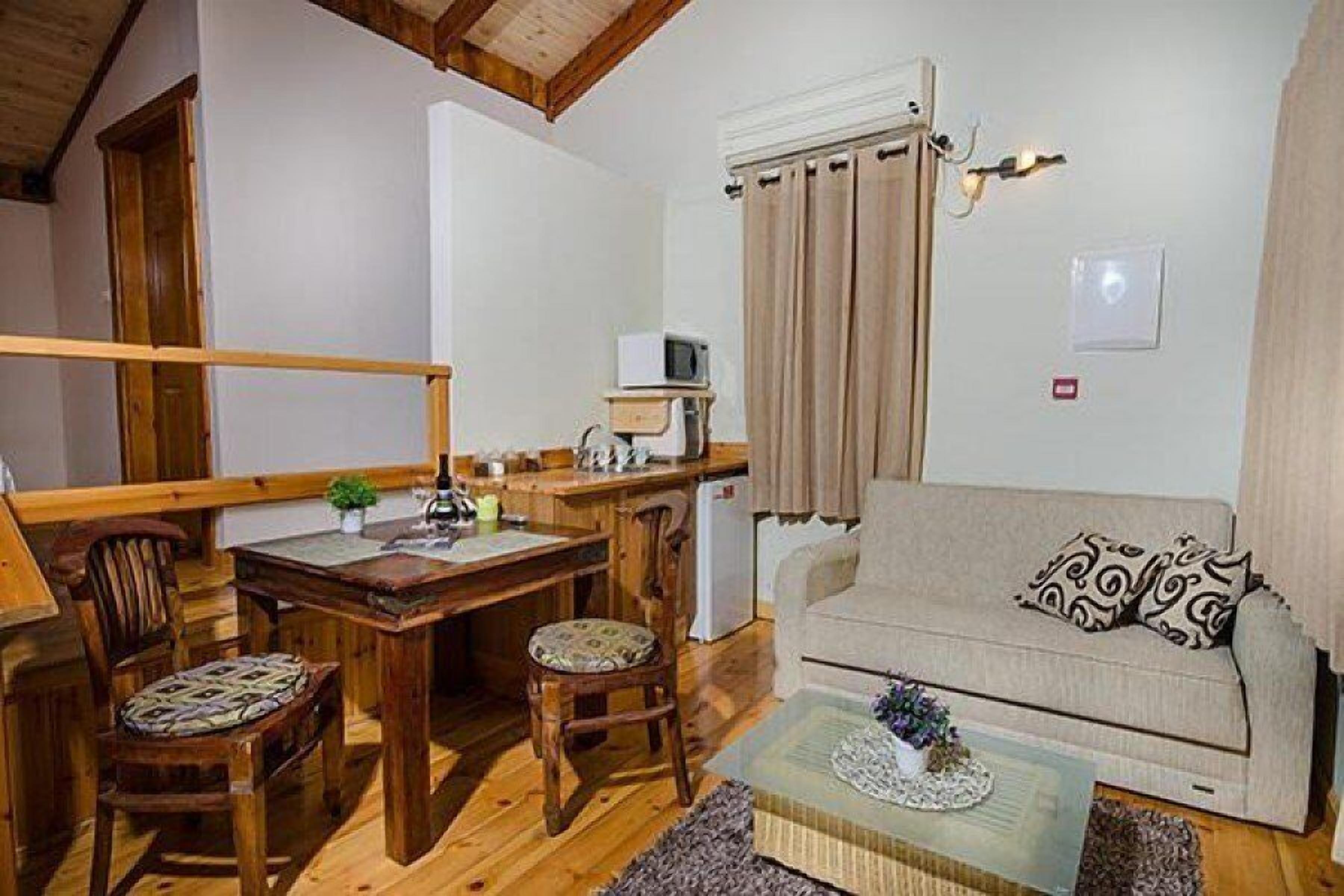 Una sala de estar acogedora con una mesa de comedor de madera, dos sillas, un sofá y un televisor pequeño.
