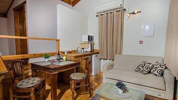 Una sala de estar acogedora con una mesa de comedor de madera, dos sillas, un sofá y un televisor pequeño.