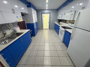 Una cucina con mobili blu, un lavello, un fornello e un forno a microonde.