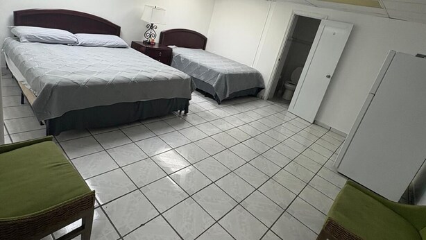Ein Zimmer mit zwei Betten, einem kleinen Tisch mit Lampe, einer Tür und einem weißen Schrank.