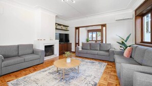 A spacious living room with two grey sofas, a wooden coffee table, and a fireplace. - Villa 7BR/7BA with Pool & Backyard Prime Location! (Vila Nova de Gaia)