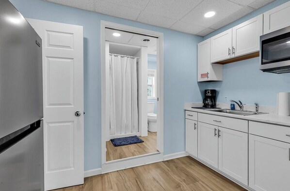 A compact kitchen with white cabinets, a microwave, and a coffee maker.
