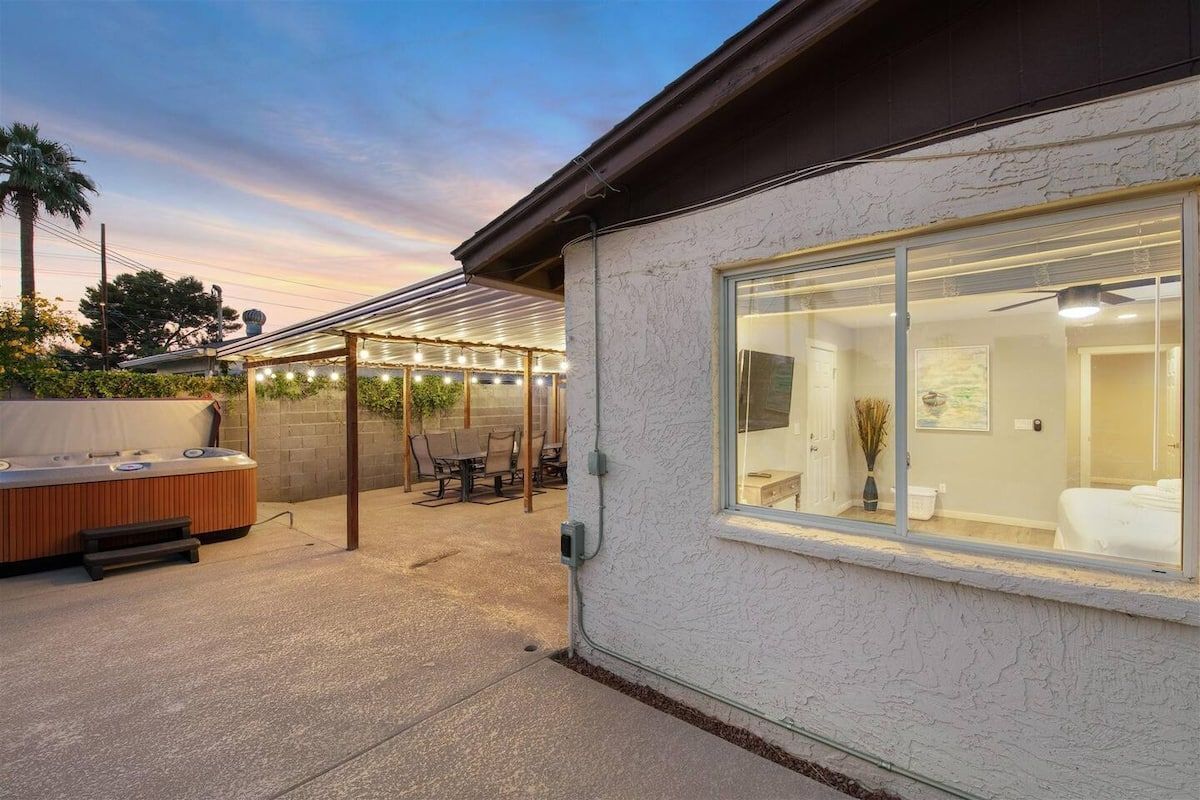 Un patio exterior cubierto con jacuzzi, zona de estar y una habitación con cama, totalmente cerrada con vidrio.
