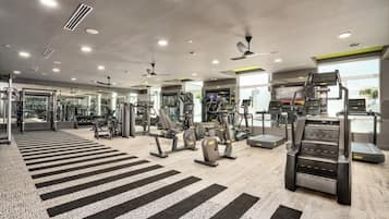 Una palestra moderna con diverse attrezzature per l'allenamento, ampie finestre e un pavimento a righe.