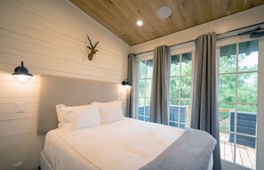 A bedroom with a bed, a mounted animal head, and a window with curtains. - Modern Cabin w/ Forest View & Access 70+ Amenities (Richmond)