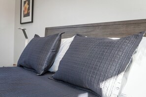 A neatly made bed with a dark gray quilt and pillows, a wooden headboard, and a framed picture on the wall. - Exceptional Vacation Home - 1 bdr in Torrey, UT near Capital Reef National Park (Torrey)