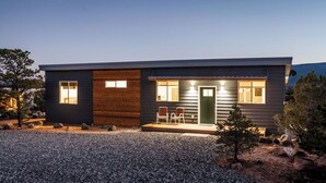 A modern house with a gravel driveway, wooden exterior, and a small porch with two chairs. - Exceptional Vacation Home - 1 bdr in Torrey, UT near Capital Reef National Park (Torrey)
