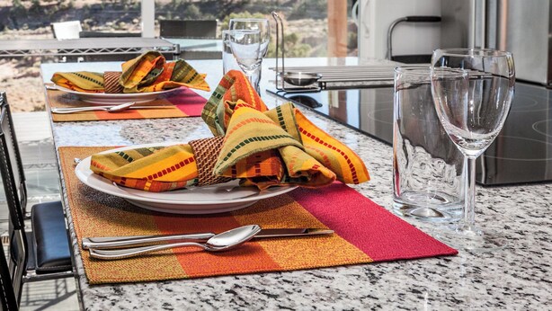 A dining table set with colorful napkins, plates, and cutlery, with a wine glass and a view of the outdoors. - Exceptional Vacation Home - 1 bdr in Torrey, UT near Capital Reef National Park (Torrey)