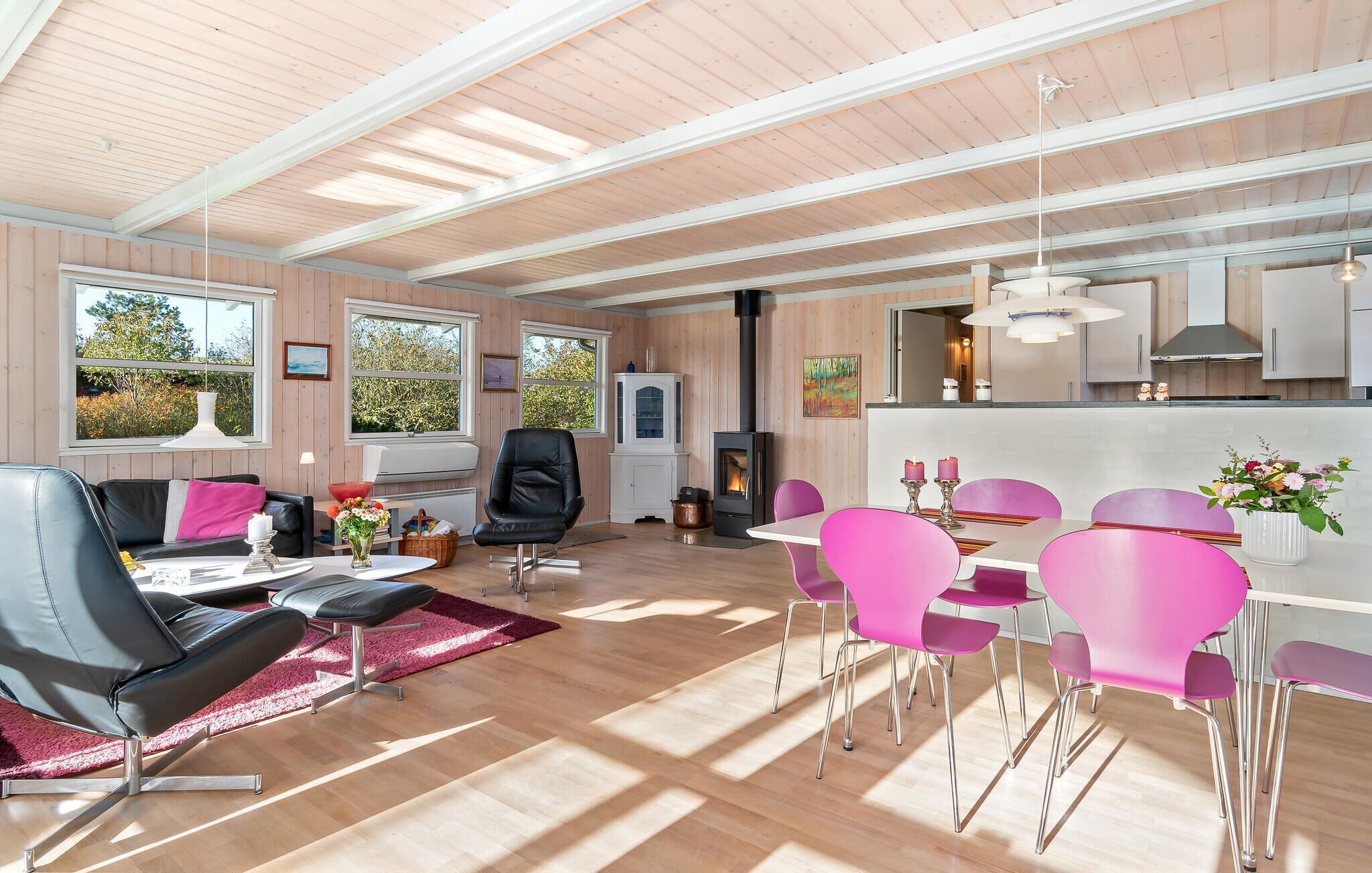 A modern living room with a fireplace, dining area, and kitchen.
