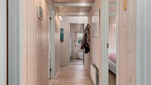 Een smalle gang met houten wanden en een houten vloer, die leidt naar een kamer met een stapelbed.