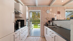 Een moderne keuken met houten wanden, een zwart aanrecht en uitzicht op een tuin.