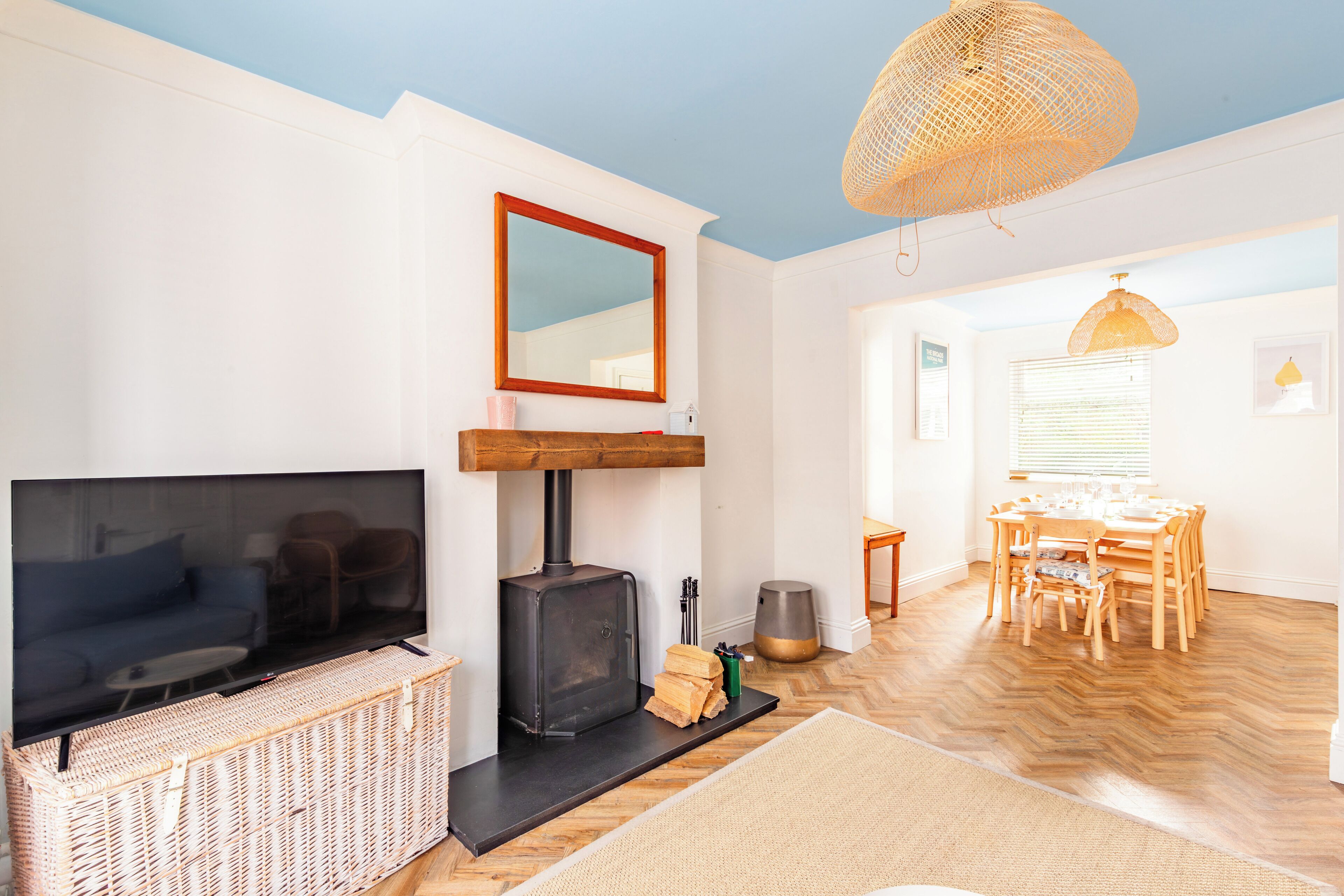 Ein Wohnzimmer mit Fernseher, Kamin, Esstisch und Stühlen.