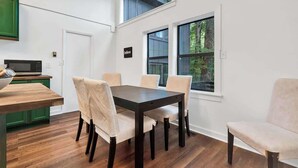 A modern kitchen with a wooden table and chairs, a microwave, and a green cabinet.