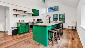 A modern kitchen with green cabinetry, a wooden island, and a bar area.
