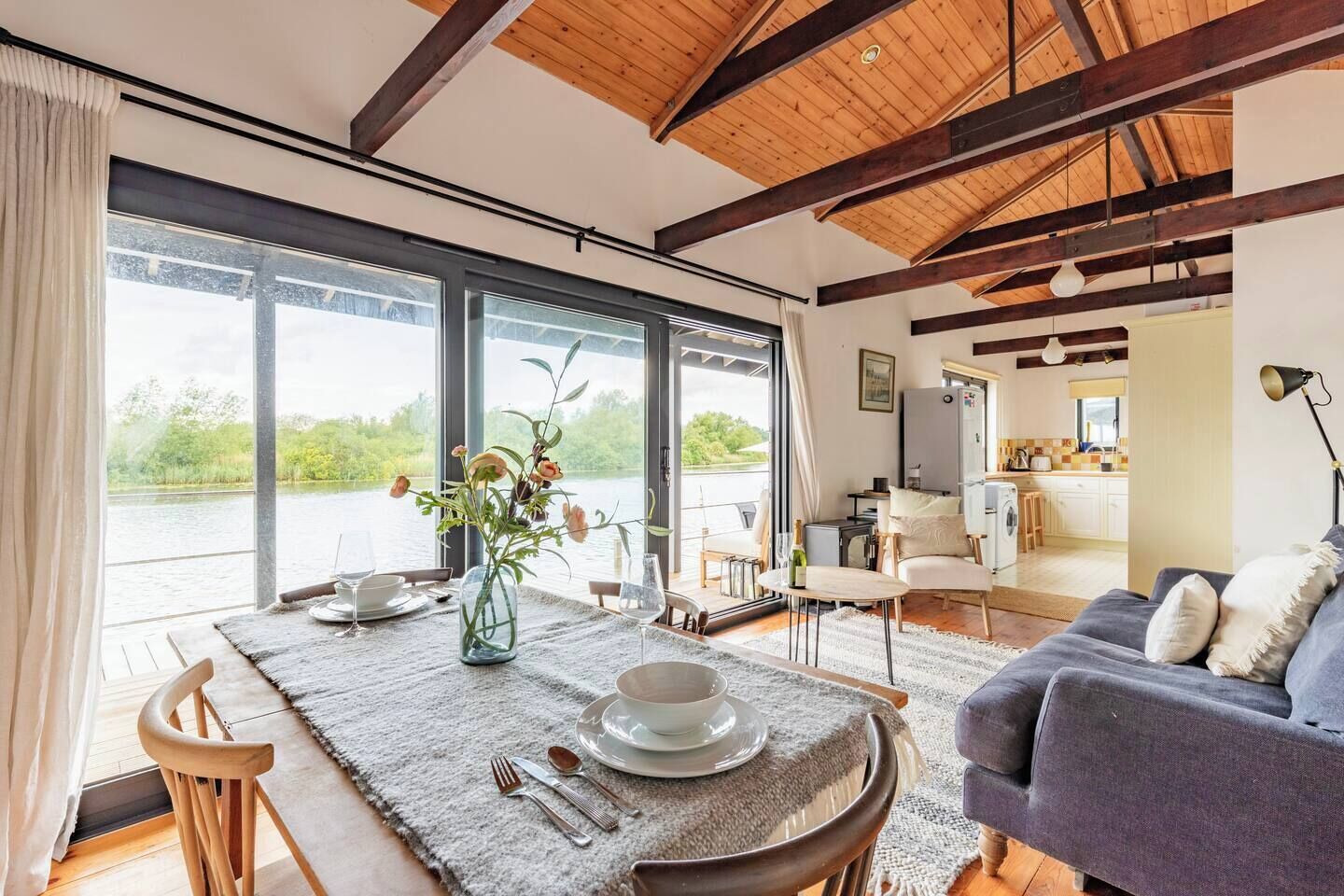 Un salon moderne avec un coin repas, de grandes fenêtres et une vue sur un lac.