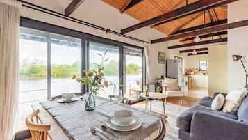Un salon moderne avec un coin repas, de grandes fenêtres et une vue sur un lac.
