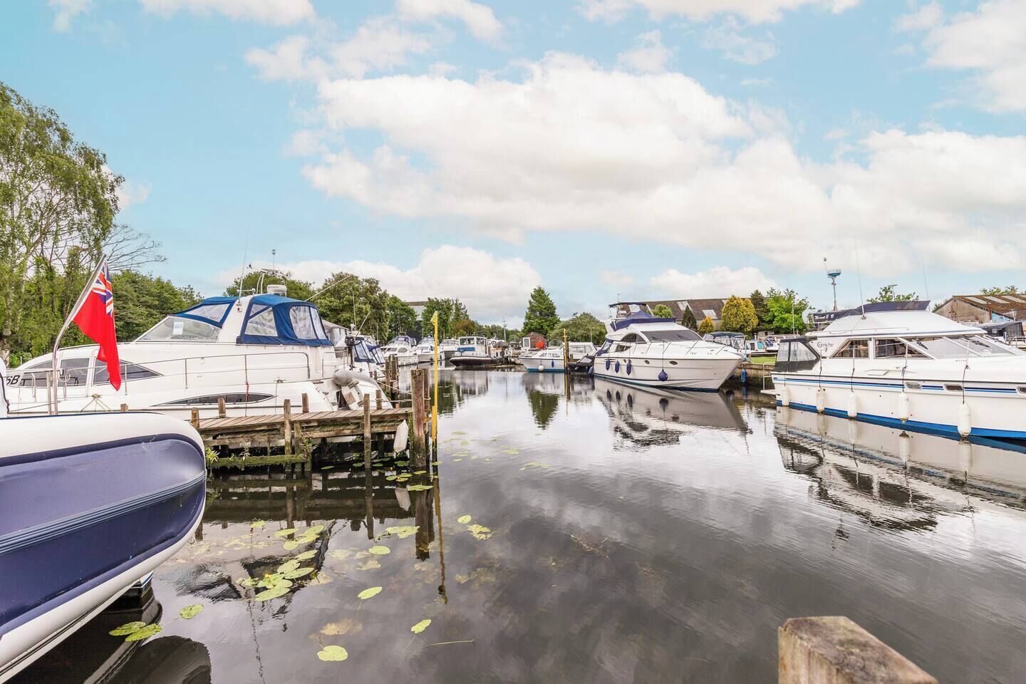 Un port de plaisance où sont amarrés plusieurs bateaux, l’eau est calme et le ciel est dégagé.