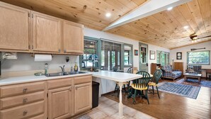 A spacious kitchen with wooden cabinets, a large island, and a dining area with chairs and a sofa. - Lakefront Cabin on Watts Bar Lake | Private Dock & Views (Roane County)