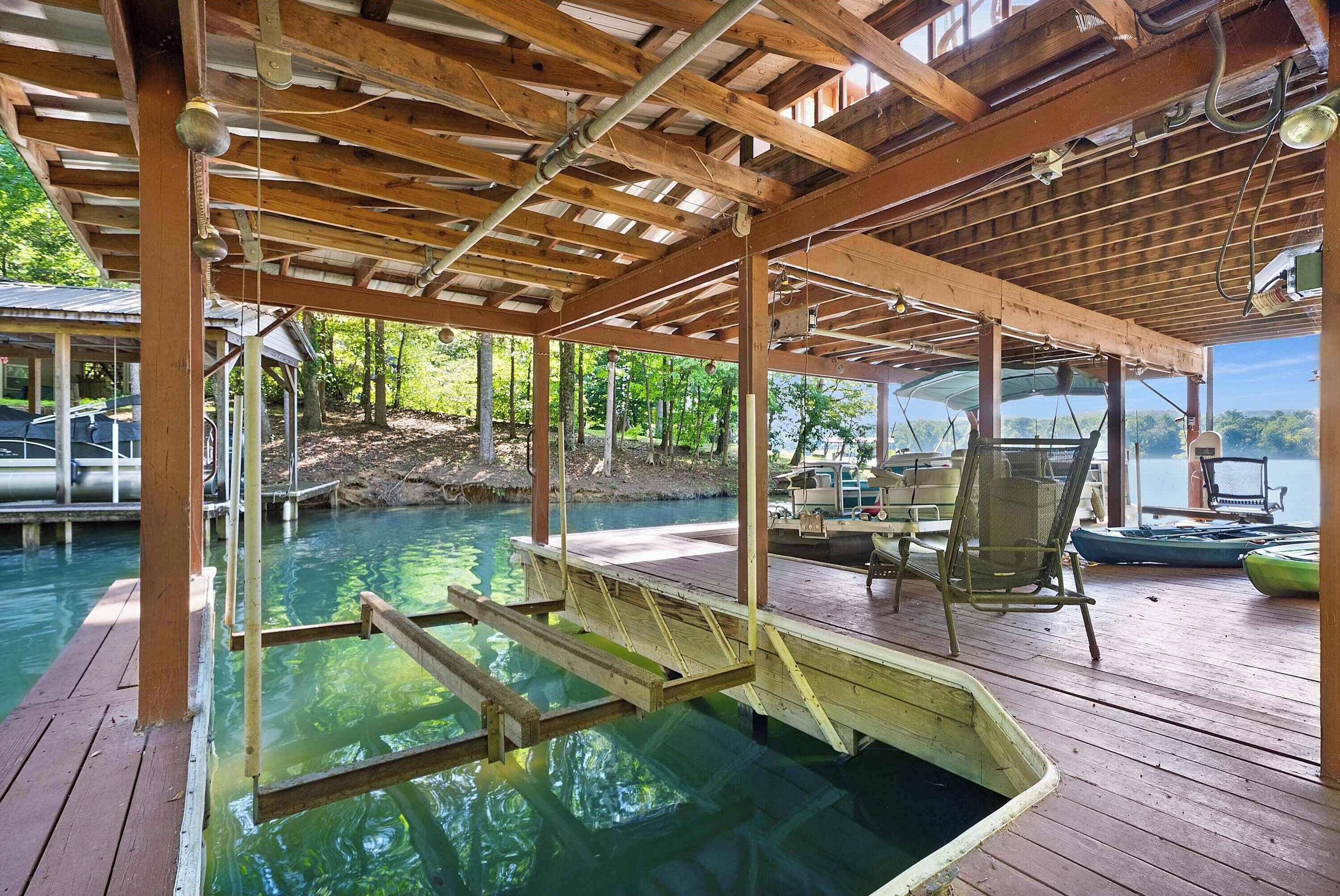 Una terraza de madera con piscina, sillas y vista al agua.