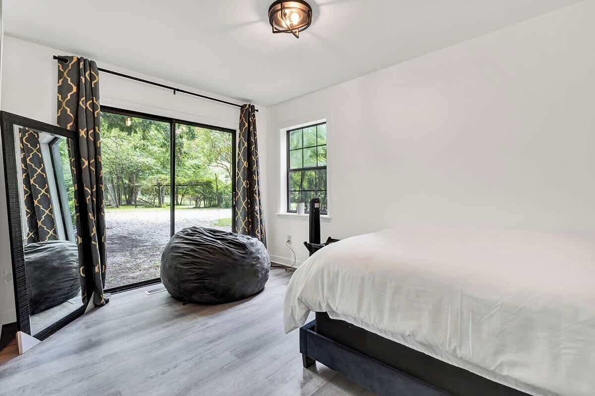 Un dormitorio con una cama grande, un sillón informal y vistas a zonas verdes a través de amplios ventanales.