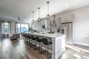 A modern kitchen with a large island, bar stools, stainless steel appliances, and pendant lighting. - Stylish Southside Home in the Heart of Chattanooga (Chattanooga)