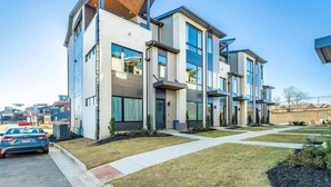 Un moderno edificio residencial de varios pisos con un diseño limpio y contemporáneo, que cuenta con grandes ventanales y un césped bien cuidado.