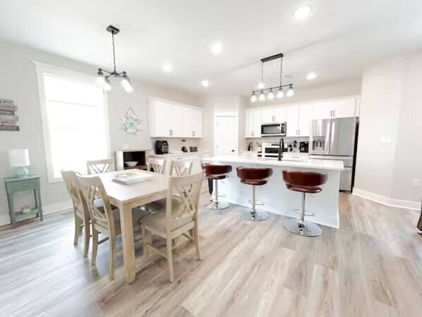 A modern kitchen with white cabinets, a central island, and bar stools.