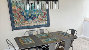 Een eetruimte met een tafel, stoelen, een hanglamp en een grote muurschildering.