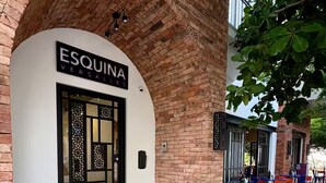 A brick building with a white facade and a black-framed entrance labeled "ESQUINA VERSAILLES". - Versalles Corner (Puerto Vallarta)