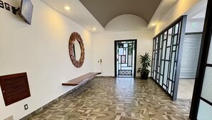 A spacious hallway with patterned flooring, a large mirror, and a bench. - Versalles Corner (Puerto Vallarta)