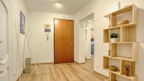 Um corredor com porta de madeira, parede branca com sinal de WiFi e prateleira de madeira com objetos decorativos.