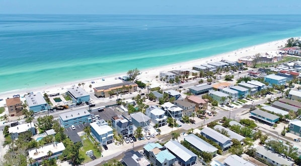 A coastal residential area with beachfront properties, roads, and clear blue waters.