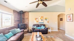 A living room with a fireplace, a sofa, a coffee table, and a ceiling fan. - Zion's Edge! Entire Home with Views, 20 Min from Zion N.P., Sleeps 10 (La Verkin)