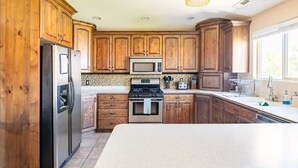 A kitchen with wooden cabinets, stainless steel appliances, and a large island. - Zion's Edge! Entire Home with Views, 20 Min from Zion N.P., Sleeps 10 (La Verkin)
