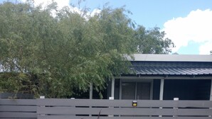 A fenced area with a gravel ground, a wooden fence, and a building with a metal roof in the background. - Studio 1 Je Nous between the Sea and the Lagoon (Faro de José Ignacio , la Juanita)