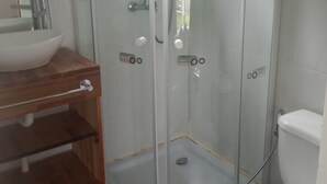 A bathroom with a glass-enclosed shower, a white toilet, and a wooden vanity with a sink. - Studio 1 Je Nous between the Sea and the Lagoon (Faro de José Ignacio , la Juanita)