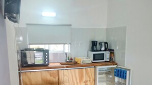 A compact kitchen with a wooden table and stools, a microwave, a coffee maker, and a refrigerator. - Studio 1 Je Nous between the Sea and the Lagoon (Faro de José Ignacio , la Juanita)