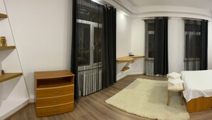 A bedroom with a large bed, bedside tables, a wooden dresser, and a window with curtains. - Casa din Tei Brasov by BuySellRent (Brașov)