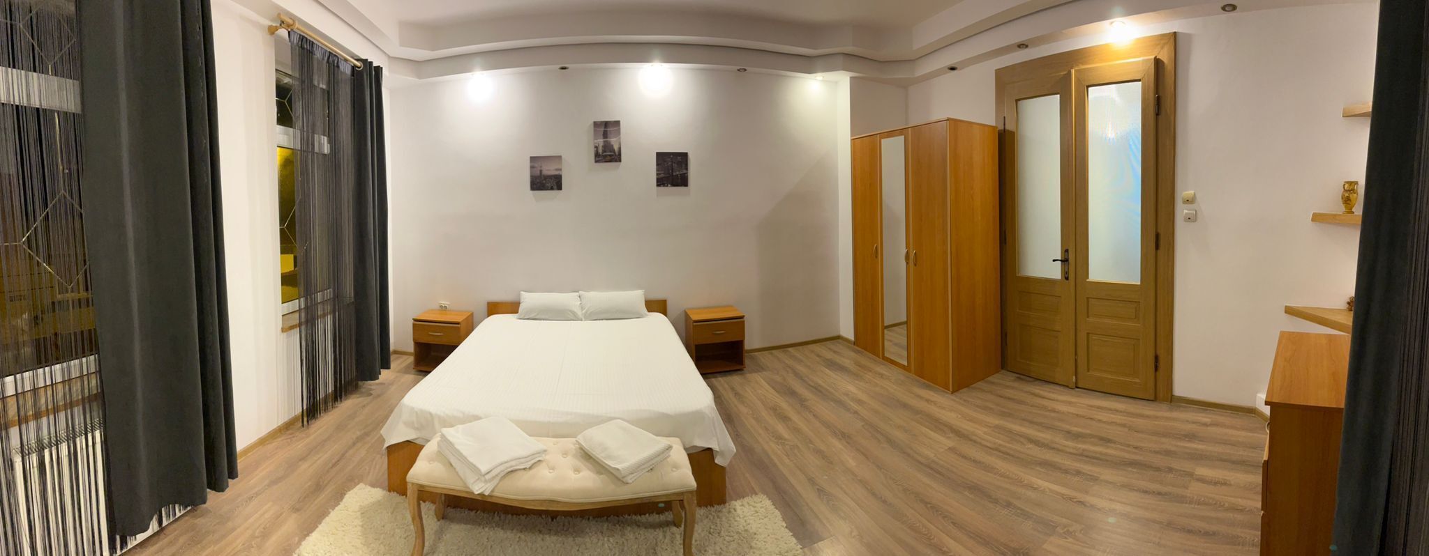 A bedroom with a bed, bedside tables, a wardrobe, and a mirror.