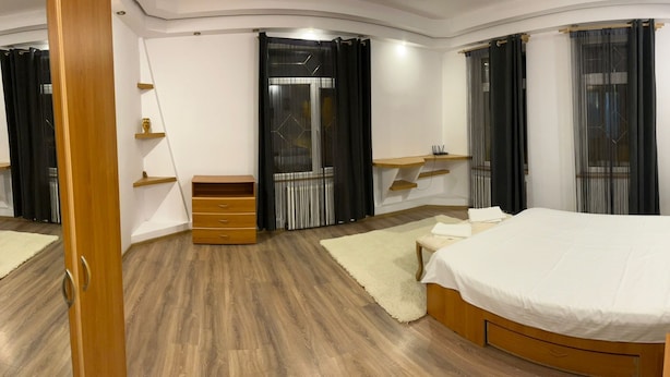 A modern bedroom with a large bed, wooden furniture, and a built-in shelf. - Casa din Tei Brasov by BuySellRent (Brașov)