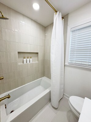 A modern bathroom with a bathtub, a shower curtain, and a toilet.