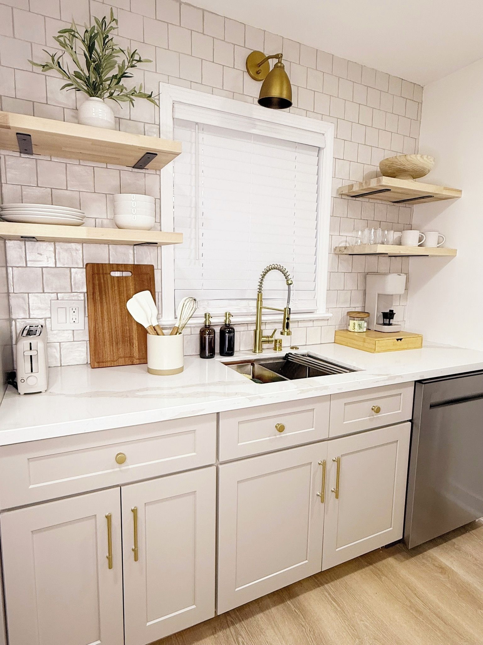 A kitchen with white cabinetry, a stainless steel sink, and a white countertop.